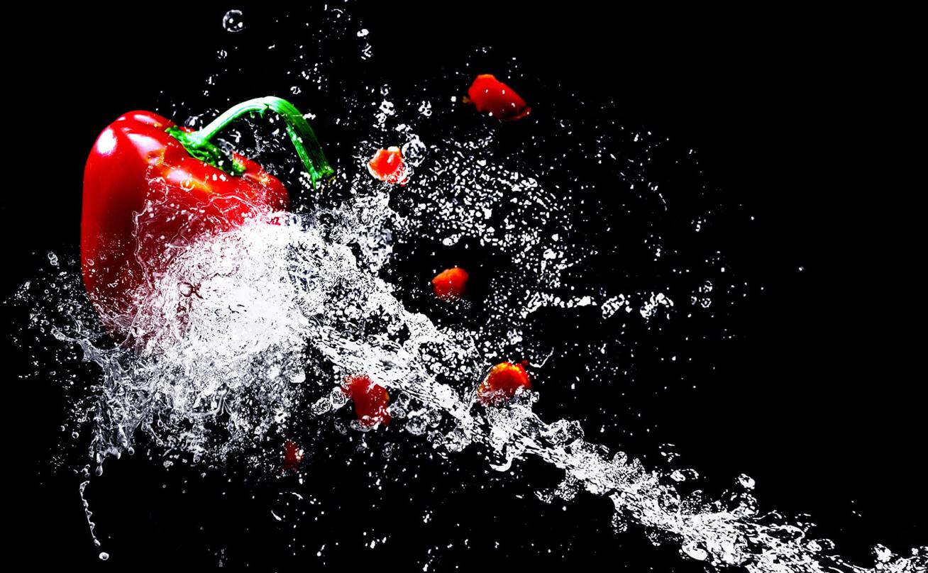 Red bell pepper being hit with jet of water
